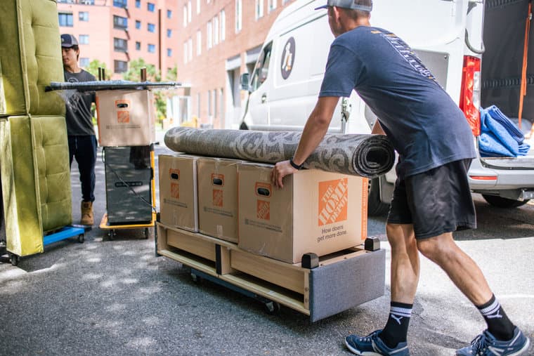 Movers carrying furniture past a Denver apartment building