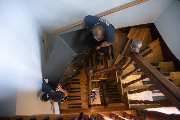 A Small Haul mover carrying a mattress down a narrow apartment staircase