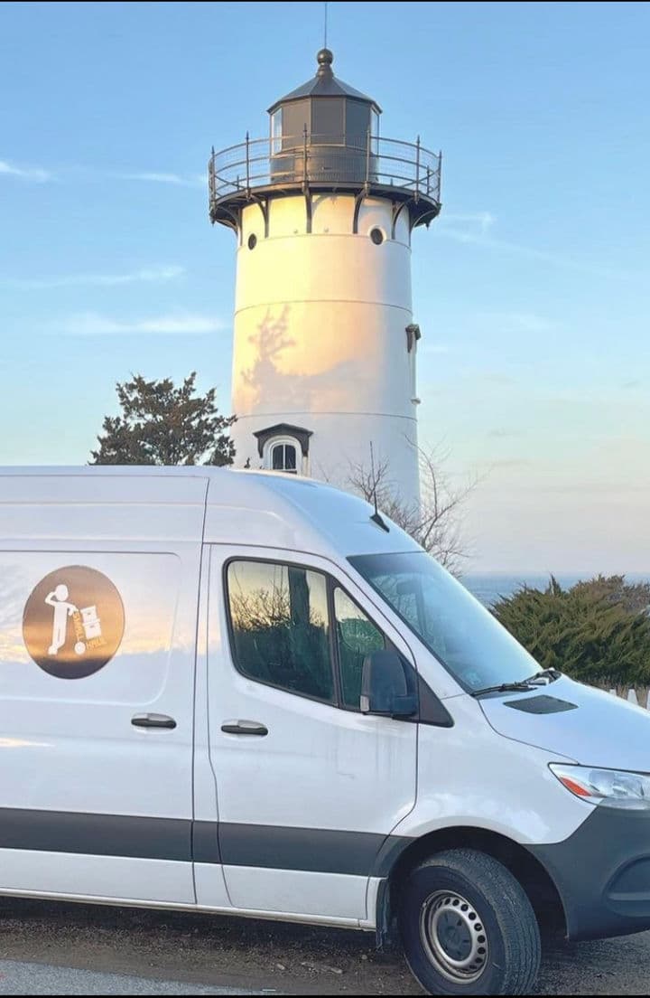 Small Haul van parked beneath a lighthouse on Cape Cod