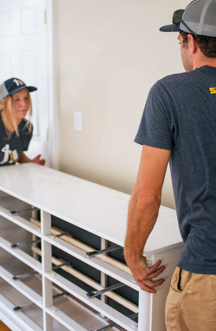Small Haul movers carrying a dresser into a home