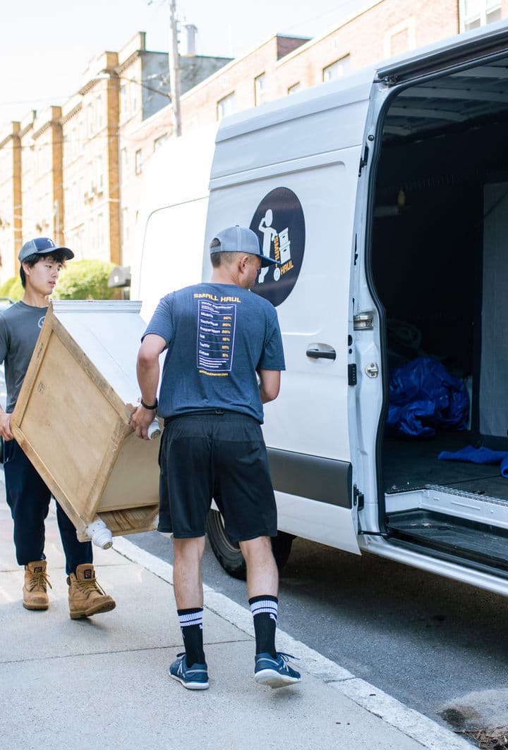 Small Haul movers carrying a piece of furniture to the van