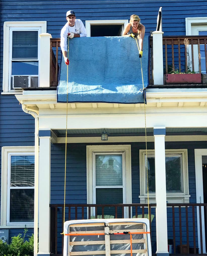A Small Haul crew lowering a couch from a triple-decker balcony in Boston
