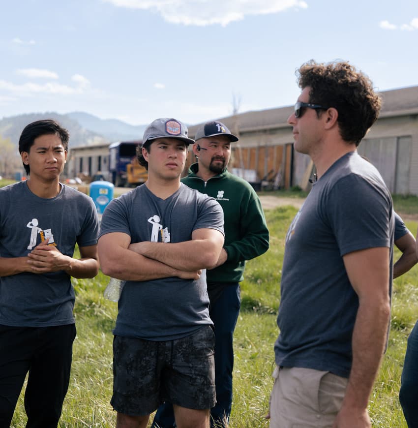 A group of Small Haul Haulers in branded tees talking on the farm